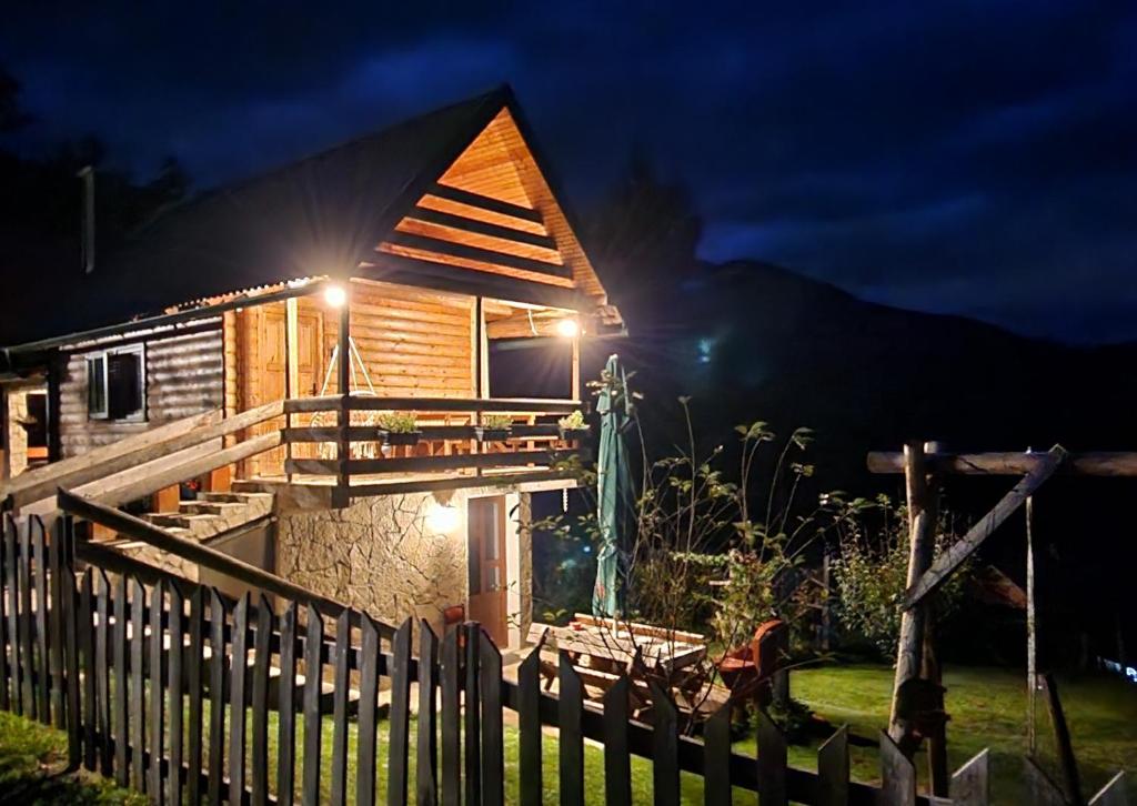 une cabane en bois avec une clôture devant elle la nuit dans l'établissement Koliba Pčelica 1, à Bijelo Polje