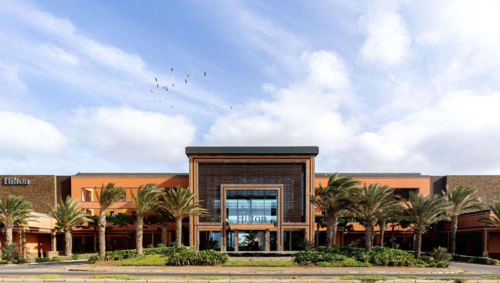 ein Gebäude mit Palmen davor in der Unterkunft Hilton Cabo Verde Sal Resort in Santa Maria