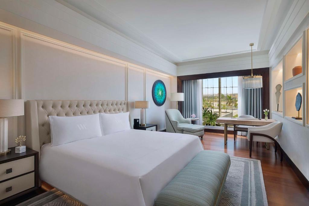 a bedroom with a large white bed and a desk at Waldorf Astoria Cairo Heliopolis in Cairo