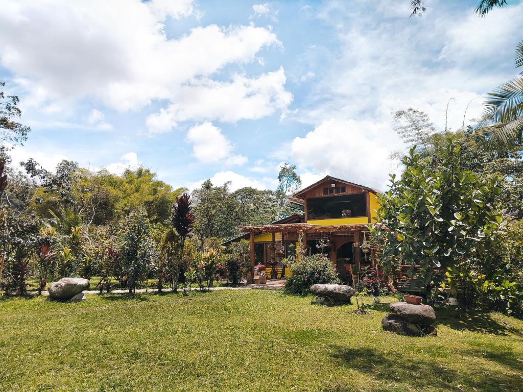 a house in the middle of a grassy yard at Senz Chalet Riverside - Mindo in Mindo