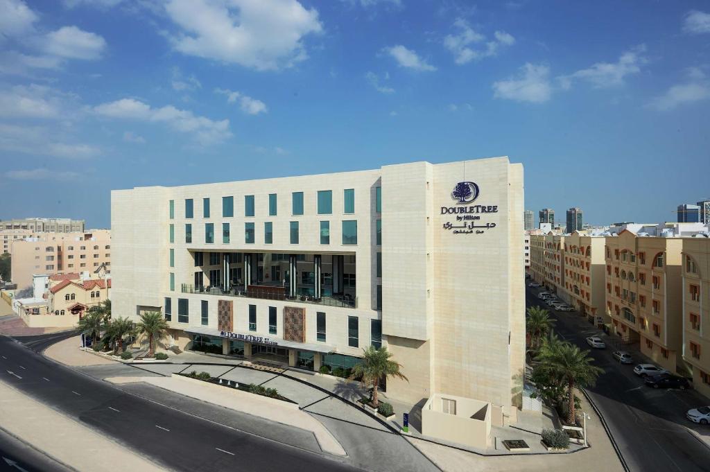 Doubletree By Hilton Doha - Al Sadd في الدوحة: مبنى ابيض كبير في مدينة بها شارع