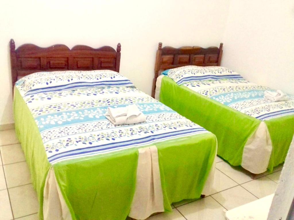 2 Betten in einem Zimmer mit grüner Bettwäsche und Handtüchern in der Unterkunft HOTEL CASA DEL REY!! in Arriaga