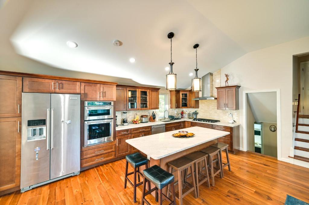 a kitchen with wooden cabinets and a large kitchen island with bar stools at Waltham Vacation Rental about 12 Mi to Downtown Boston in Waltham