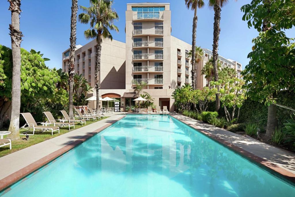 a swimming pool in front of a building with palm trees at Embassy Suites by Hilton Brea - North Orange County in Brea