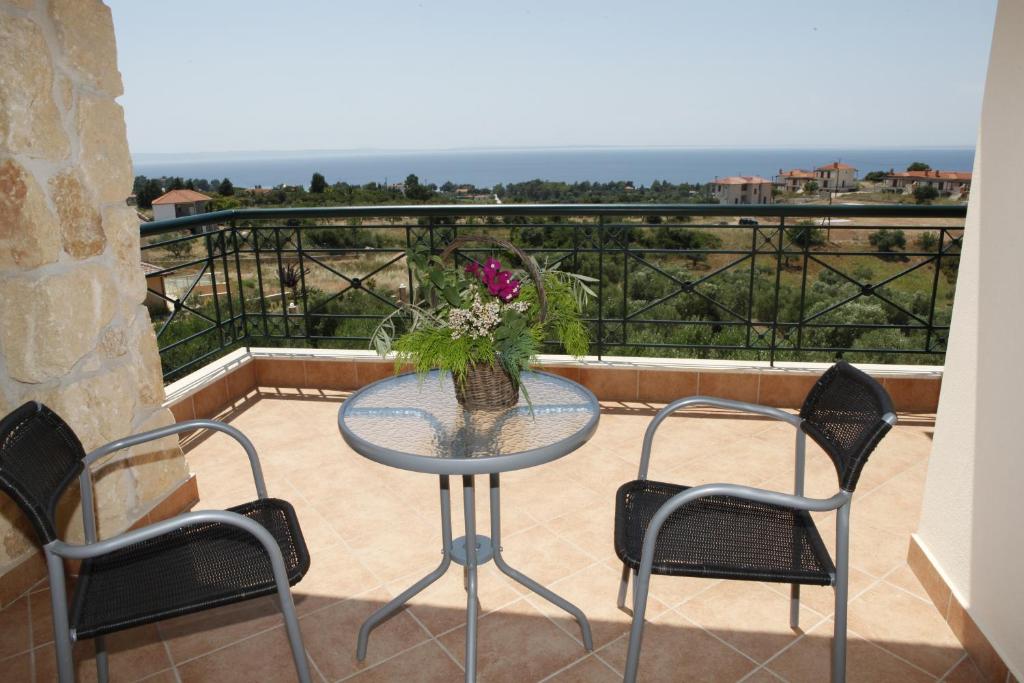 una mesa con 2 sillas y un jarrón de flores en el balcón en Sofia Luxury Maisonettes, en Nikiti
