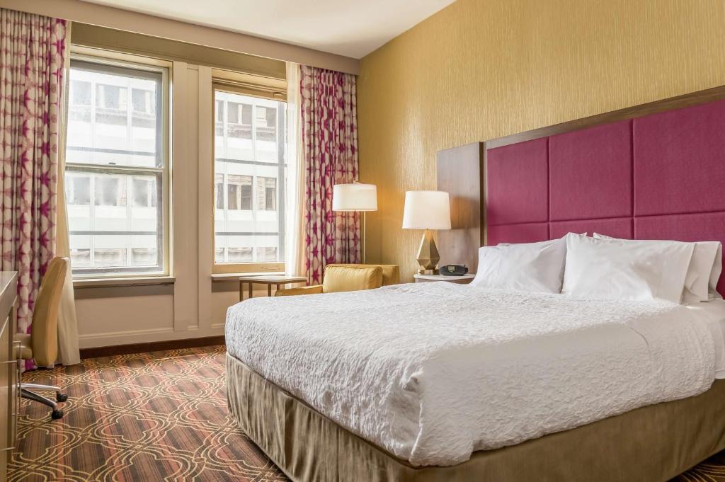 a hotel room with a large bed and a purple headboard at Hampton Inn Majestic Chicago Theatre District in Chicago