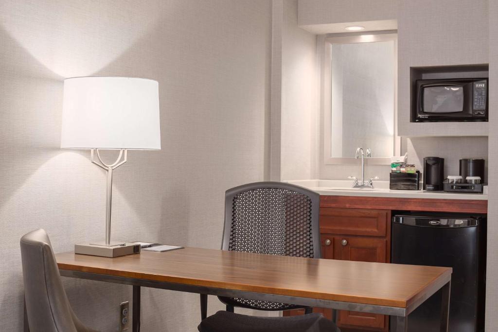 a dining room table with a lamp and a sink at Embassy Suites by Hilton Boston Marlborough in Marlborough