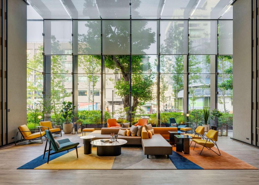 a lobby with a couch and chairs and windows at Hotel Resonance Taipei, Tapestry Collection by Hilton in Taipei