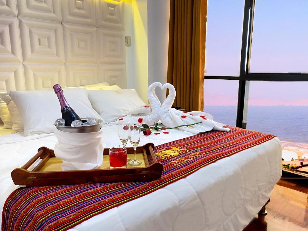- un plateau avec une bouteille de vin et des verres sur le lit dans l'établissement Inkari Apart Hotel, à Lima