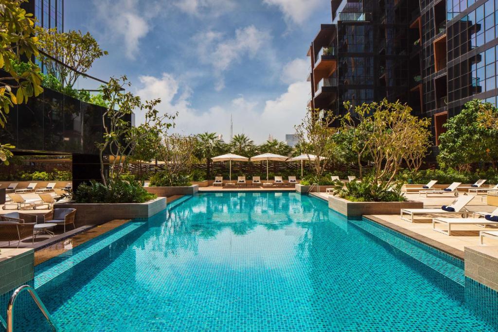 a large swimming pool with chairs and umbrellas at DoubleTree by Hilton Dubai M Square Hotel & Residences in Dubai