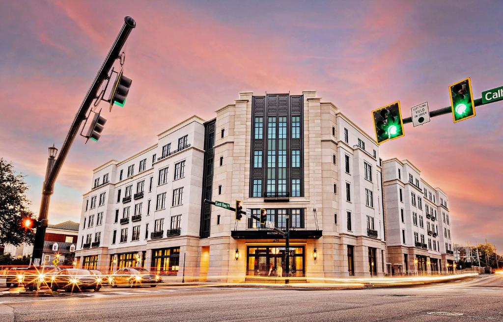 ein großes weißes Gebäude an einer Stadtstraße mit Ampeln in der Unterkunft Hilton Club Liberty Place Charleston in Charleston