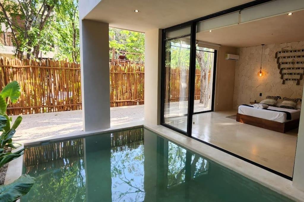 een slaapkamer en een zwembad in een huis met een bed bij Apartment with private pool Tulum in Chemuyil