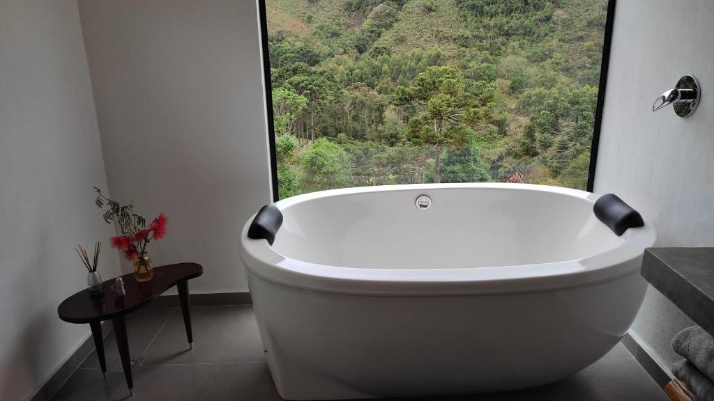 a white bath tub in a bathroom with a large window at Angatu chalé in Gonçalves