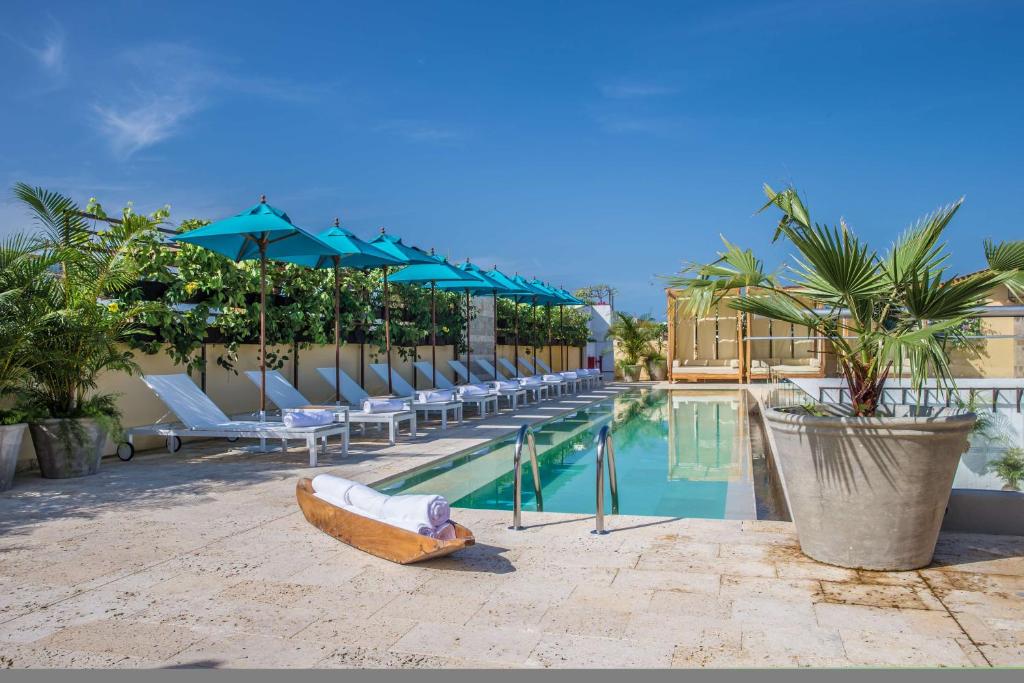 a pool with chairs and a boat next to a resort at Nacar Hotel Cartagena, Curio Collection by Hilton in Cartagena de Indias