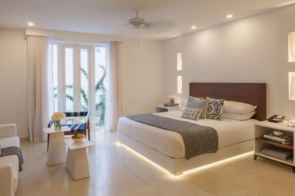1 dormitorio con 1 cama y sala de estar en Nacar Hotel Cartagena, Curio Collection by Hilton, en Cartagena de Indias