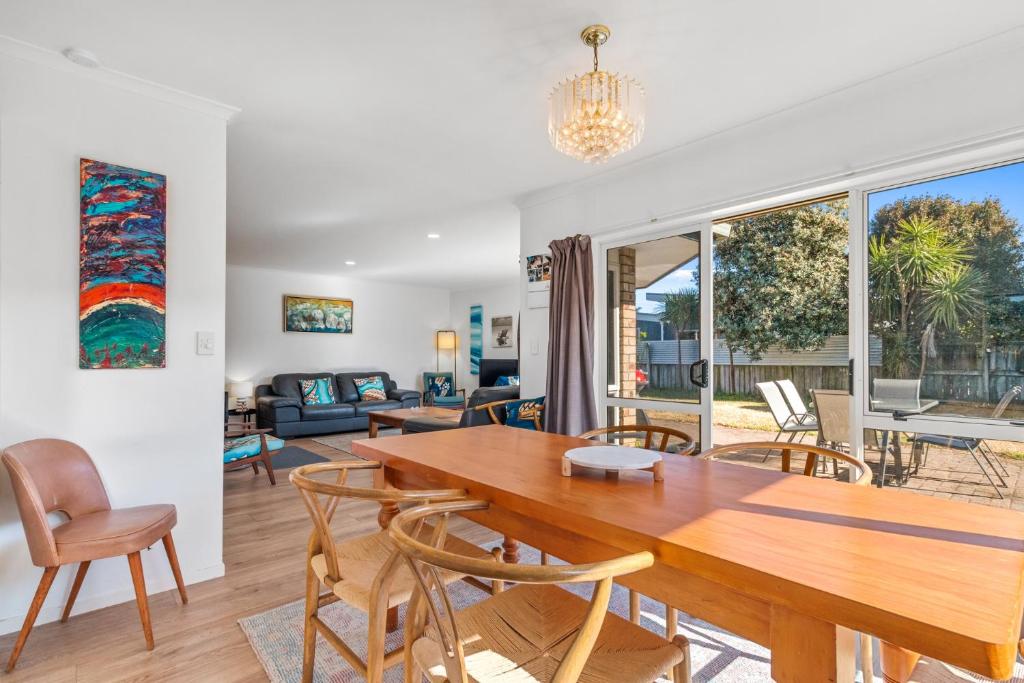 a dining room and living room with a wooden table and chairs at Fisherman's Friend - Bowentown Holiday Home in Waihi