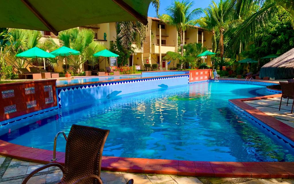 a swimming pool with chairs and umbrellas next to a hotel at Solar pipa apartments in Pipa