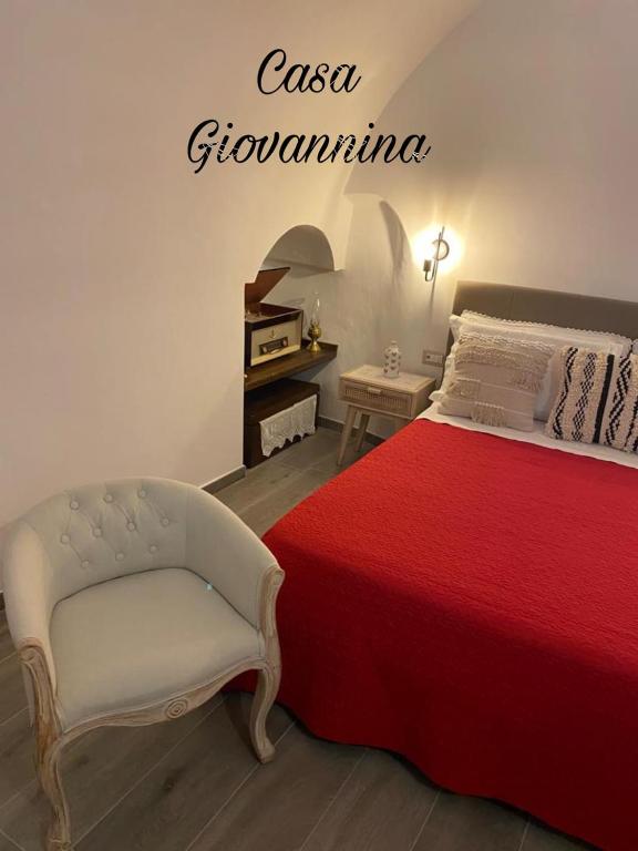 a bedroom with a red bed and a white chair at Casa Giovannina in Bernalda
