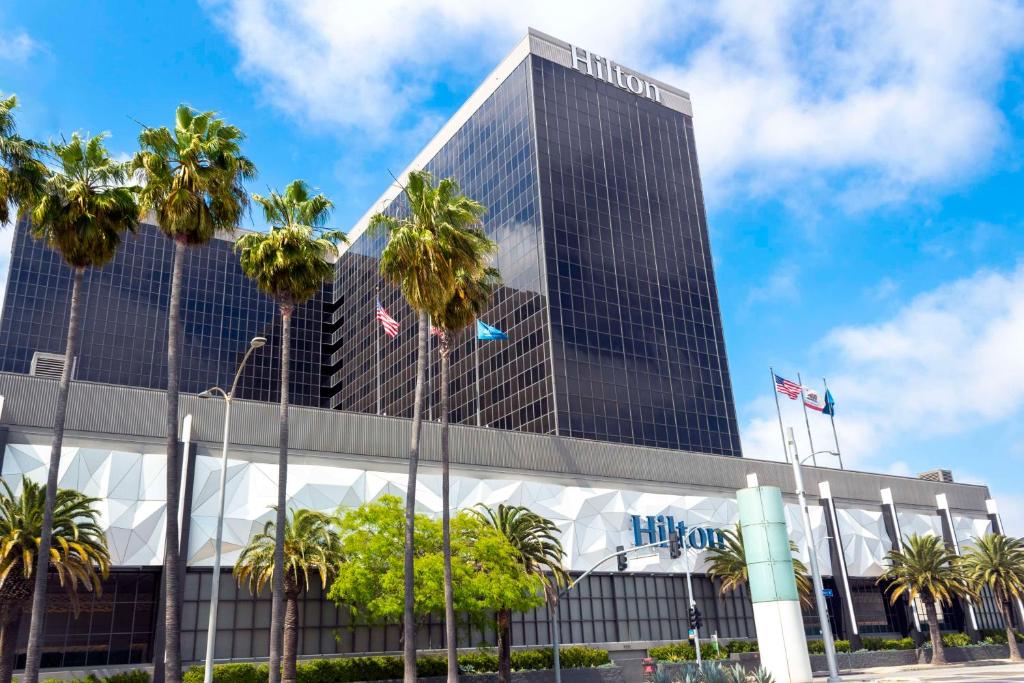 wysoki budynek z palmami przed nim w obiekcie Hilton Los Angeles Airport w Los Angeles