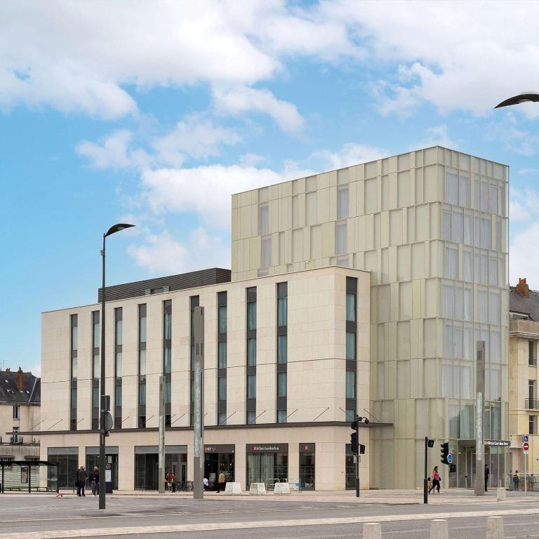a large white building on a city street at Hilton Garden Inn Tours Centre, France in Tours