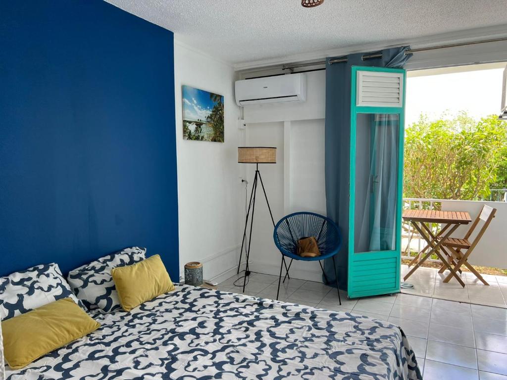 ein Schlafzimmer mit einem Bett und einer blauen Wand in der Unterkunft Studio de l'Anse Mitan in Les Trois-Îlets