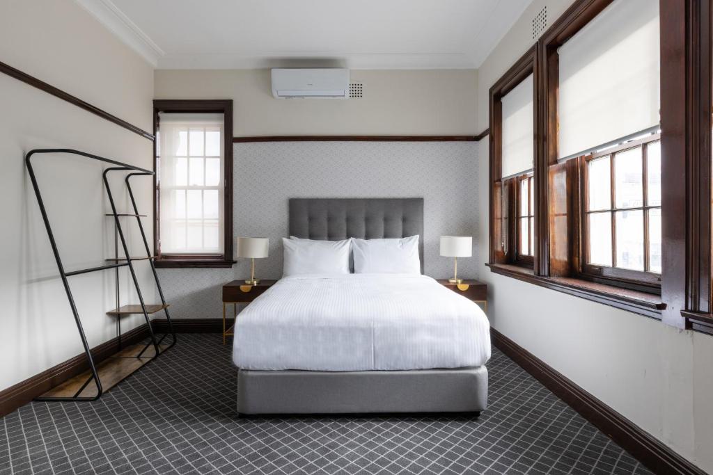Southern Cross Hotel في سيدني: غرفة نوم بسرير ابيض ونوافذ