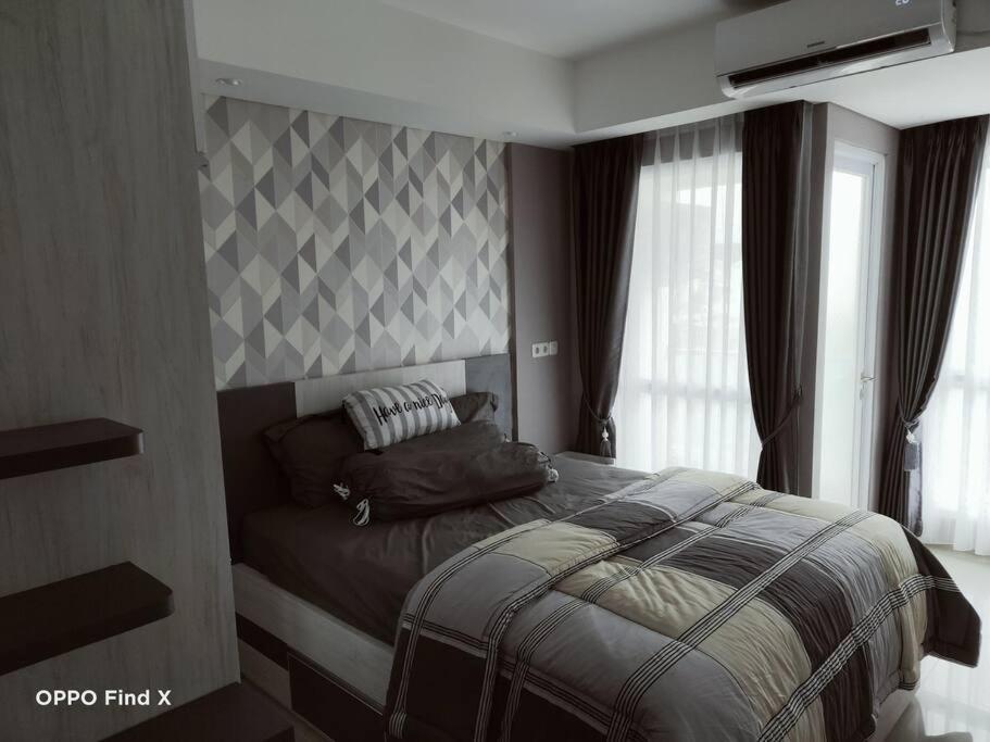 - une chambre avec un lit et un mur en damier dans l'établissement Apartemen Skylounge Makassar, à Manda