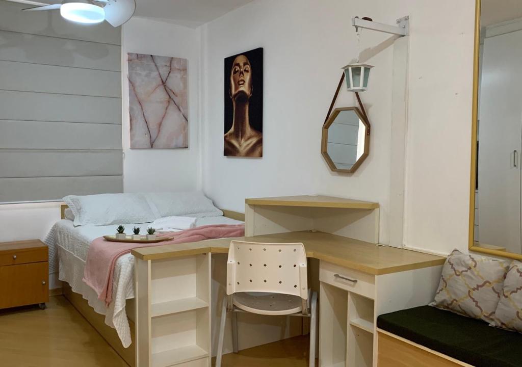 a bedroom with a desk and a bed with a mirror at Studio completo com vaga entre o Centro e Cambuí in Campinas