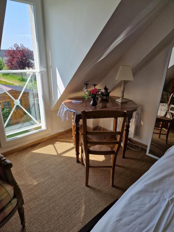 1 dormitorio con mesa, ventana y cama en Camélia rouge en Granville