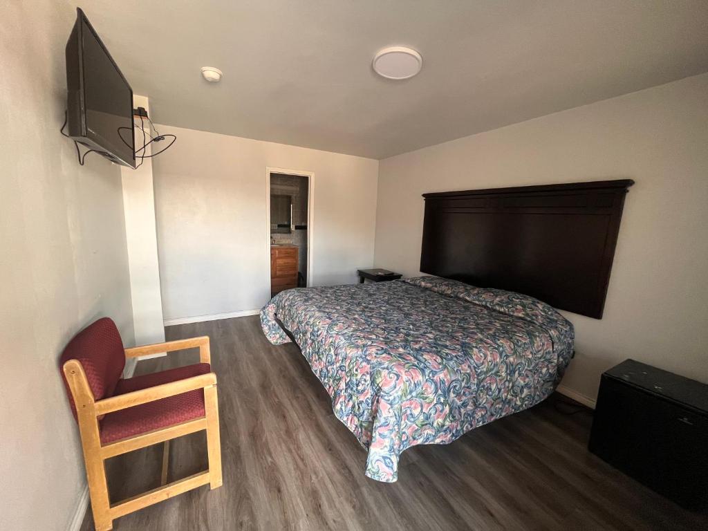 Sunrise Motel San Antonio في سان انطونيو: غرفة نوم بسرير وتلفزيون وكرسي