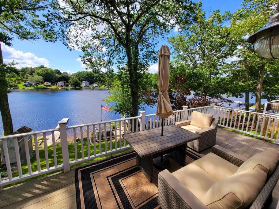 CharltonCozy Lake Cottage的带桌子和遮阳伞的木甲板