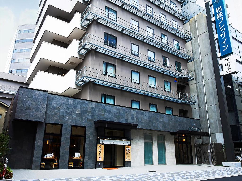 un grand bâtiment avec un panneau devant lui dans l'établissement Sotetsu Fresa Inn Kitahama, à Osaka