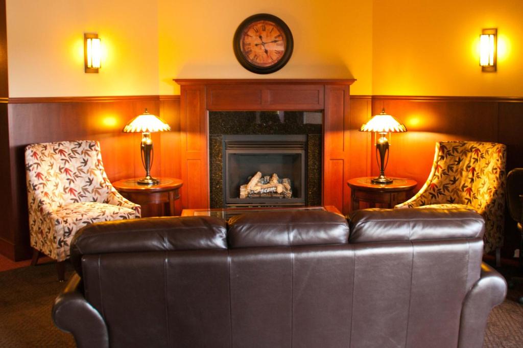 a living room with a leather couch and a fireplace at Americas Best Value Inn Big Lake Becker in Big Lake