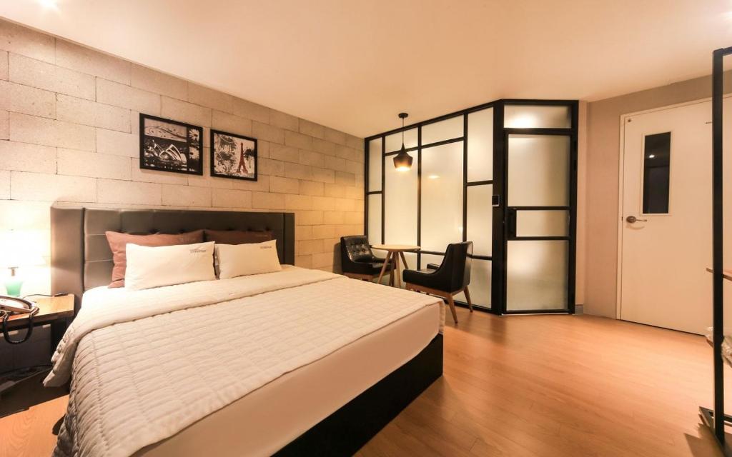 een slaapkamer met een bed, een bureau en een stoel bij Hey Day Hotel in Busan