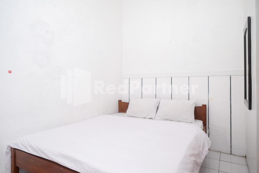 uma cama branca com lençóis e almofadas brancos em Hotel Limaran 1 Syariah Malioboro Mitra RedDoorz em Sentool