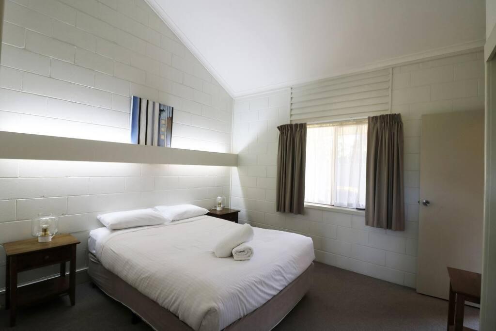 a bedroom with a white bed and a window at Micks Budget Accommodation on Fishpen in Merimbula