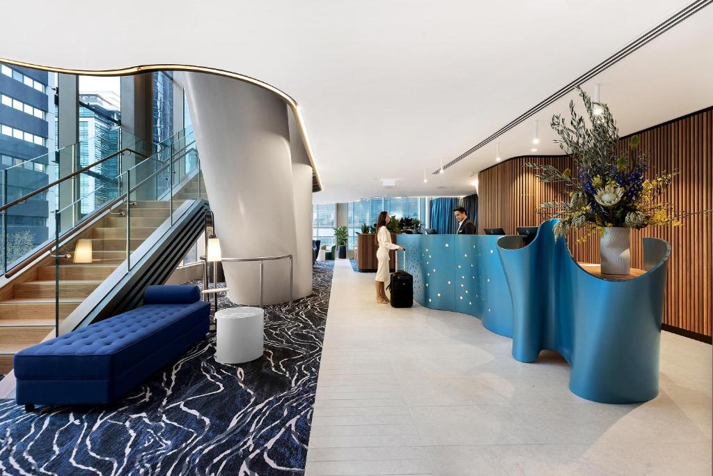 an office lobby with blue walls and a staircase at Citadines Walker North Sydney in Sydney