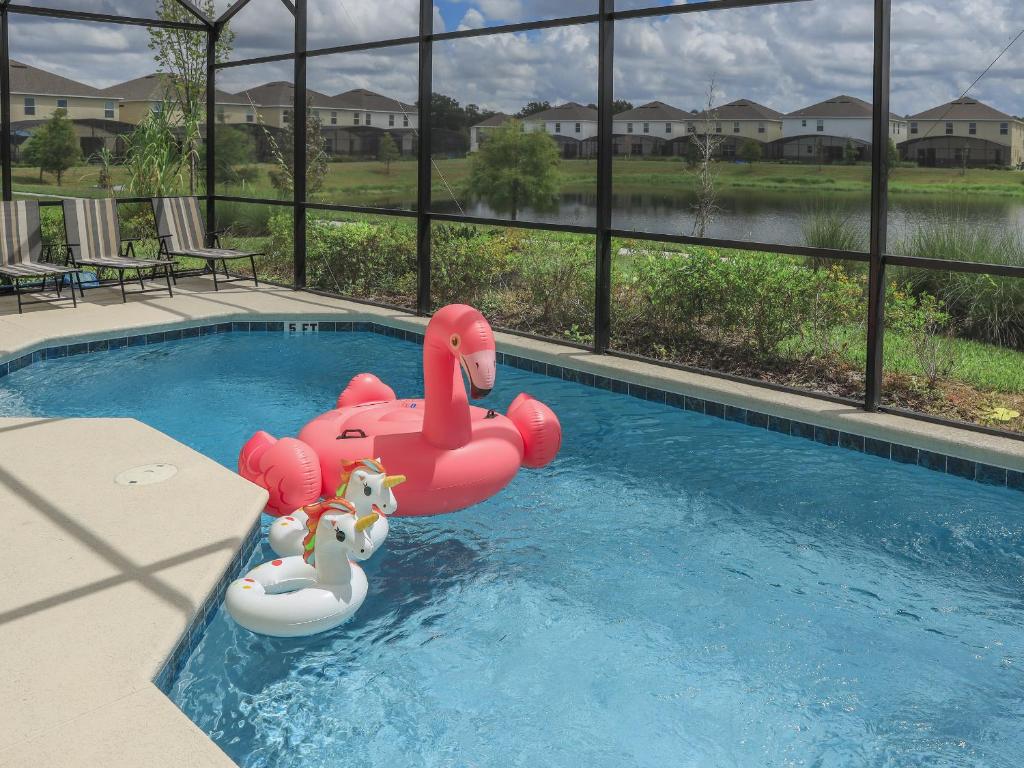 a small pool with a pink inflatablevisor in the water at Waterfront Brand New Modern Luxury 8 BR pool house! Sleeps 16 in Kissimmee