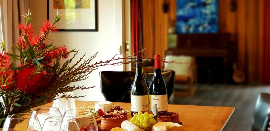 荷伯特的住宿－霍巴特入口度假屋，两瓶葡萄酒坐在带葡萄的桌子上