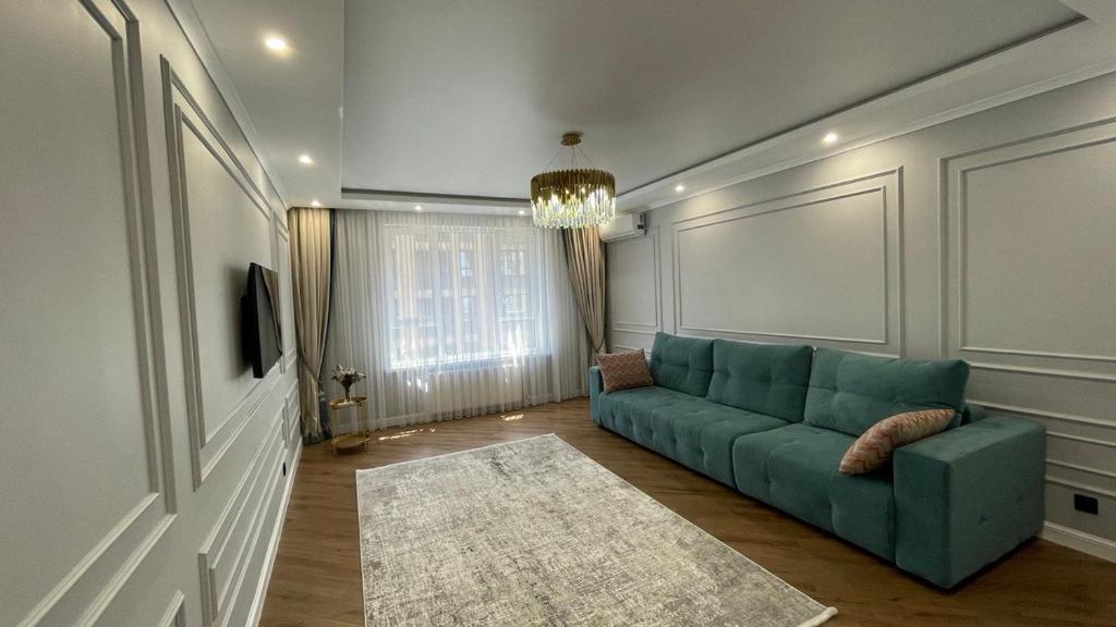 a living room with a green couch and a rug at 2х комнатные апартаменты 4-177 in Almaty