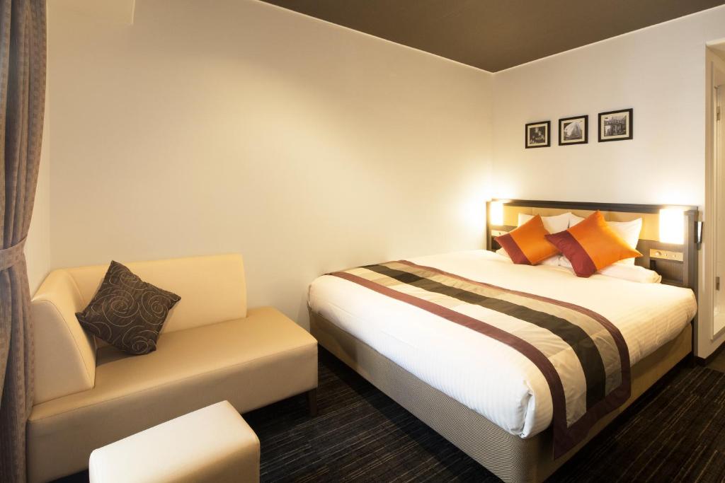 um quarto de hotel com uma cama e uma cadeira em HOTEL MYSTAYS Shinsaibashi em Osaka
