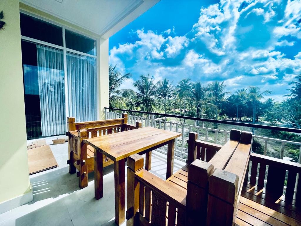 Kelingking Hostel في Klungkung: شرفة مع طاولة خشبية ومقعدين