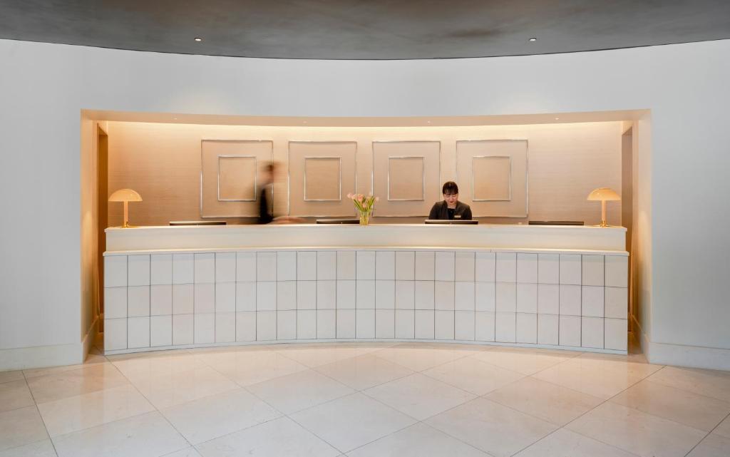 dos personas sentadas en un bar en una habitación en Amid Hotel Seoul, en Seúl