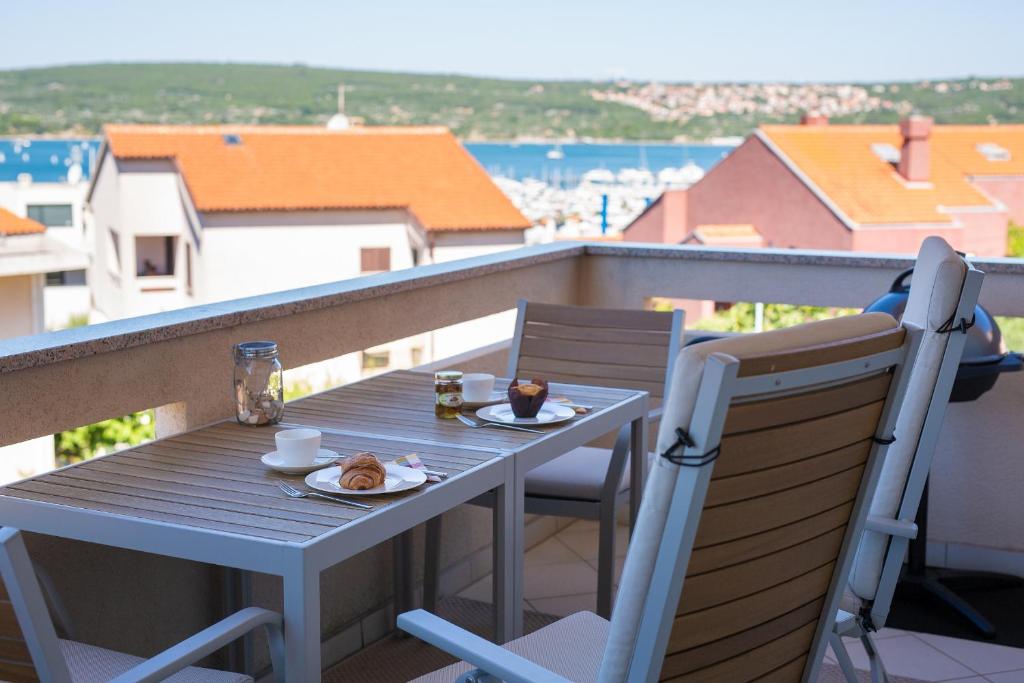 a table with a plate of food on a balcony at Sea & Wine Apartment with Terrace & Scenic Sea View, Punat in Punat