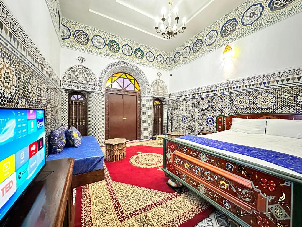 een slaapkamer met een bed en een flatscreen-tv bij Riad Blue Oasis in Fès