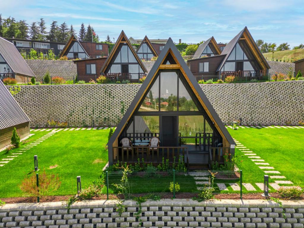 a house with a triangular roof in a yard at Aronia Bungalow in Elmalık