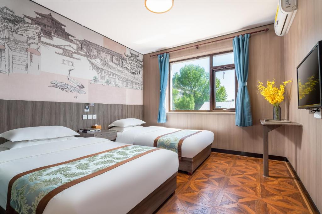 a hotel room with two beds and a tv at East Sacred Hotel-easy to findᴮᵉⁱʲⁱⁿᵍᒼᵉⁿᵗᵉʳ丨Near Tiananmen Forbidden City丨close to Metro Zhangzizhong And Beixinqiao丨 Free laundry service coffee drinks mineral water and snacks丨English language Tourism ticket service small change in Beijing