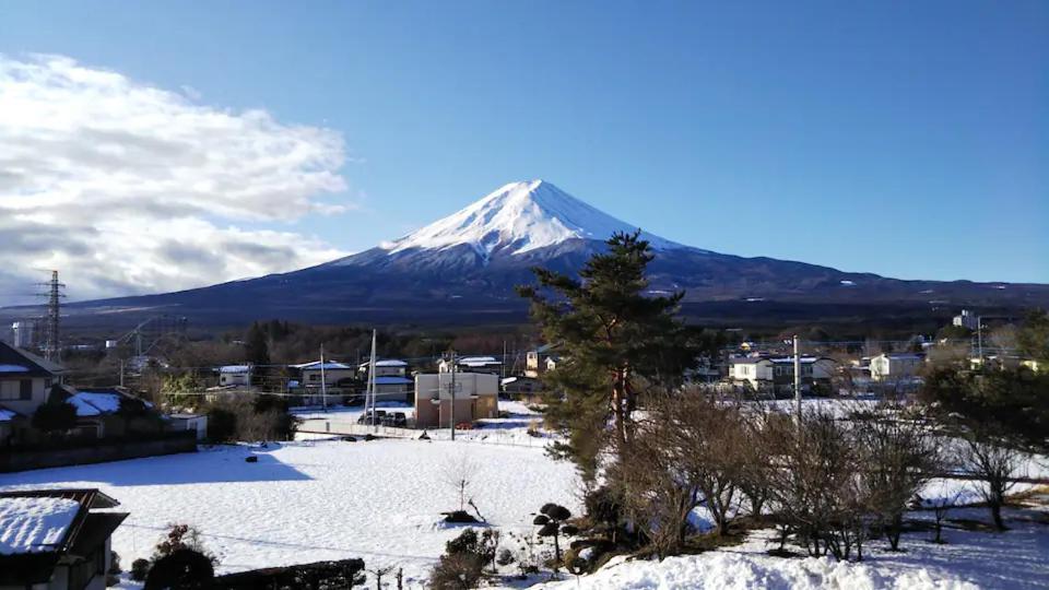 a snow covered mountain in front of a city at KAINOSATO in Fujikawaguchiko