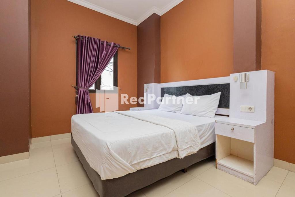 a bedroom with a white bed and a window at Star Hotel Jaksa Mitra RedDoorz in Jakarta