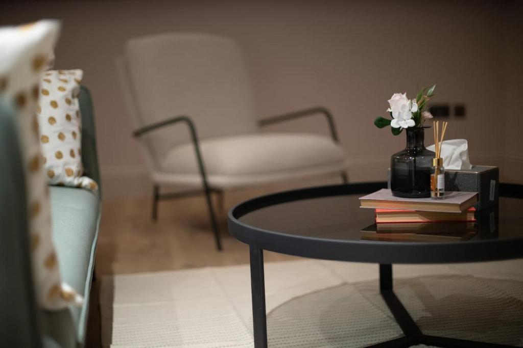 a living room with a table with books and a vase with flowers at Bella Ruiz city centre Manchester in Manchester